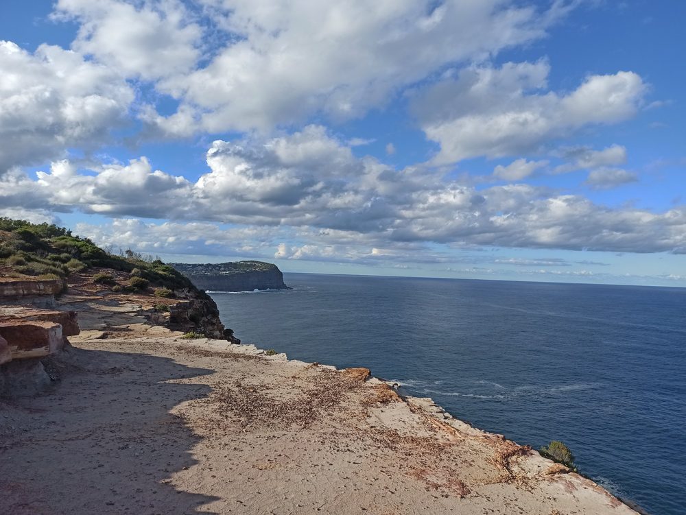 Sandstone cliff top overlooking the ocean under a cloudy sky